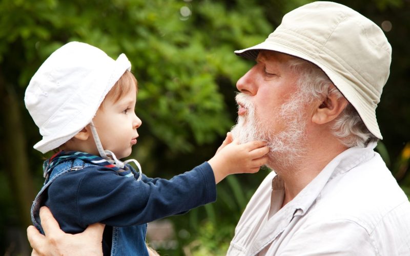 A grandfather holds his grandson in his arms.